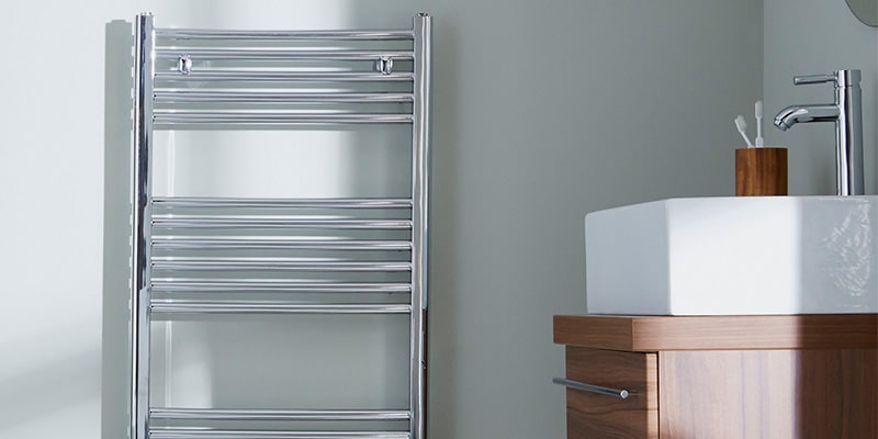 Stainless steel towel radiators hanging in bathroom against light blue wall.