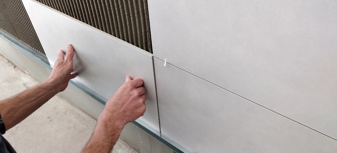 Worker laying ceramic tile on wall