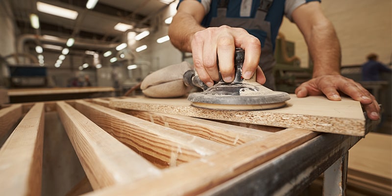 Carpenter sanding down MDF board.