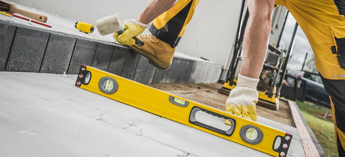 Worker in white gloves using a level to install new concrete terrace.