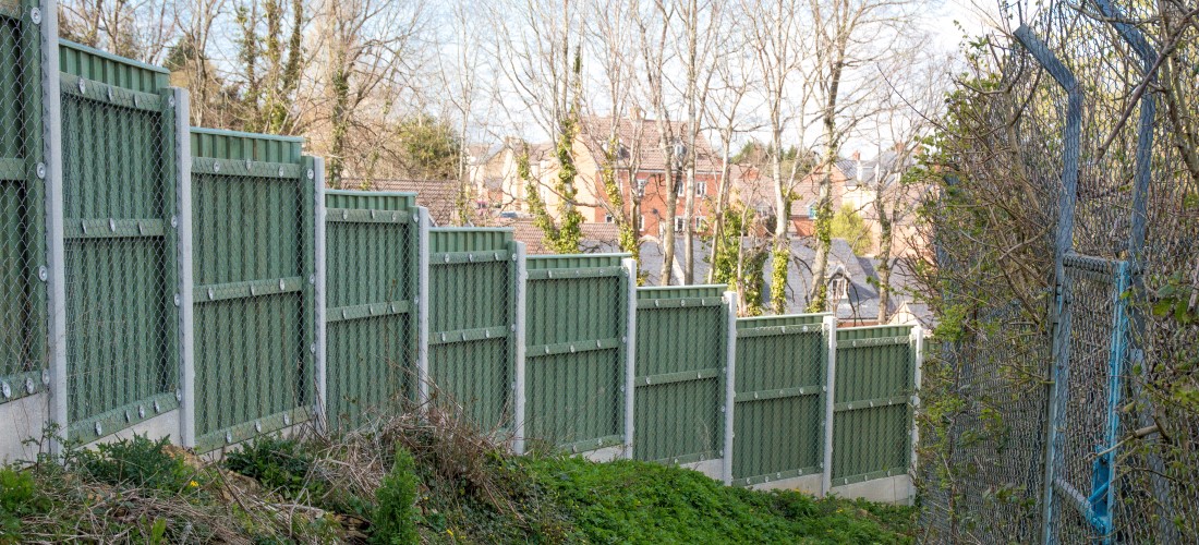 High metal fence along grass verge.