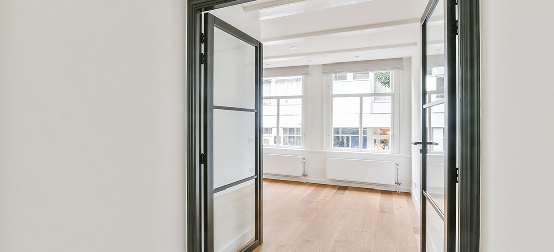Glass double interior doors leading to large, empty room.