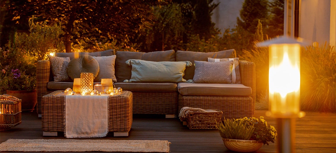 Intimate outdoor decking with three-seater sofas and warm post lights.